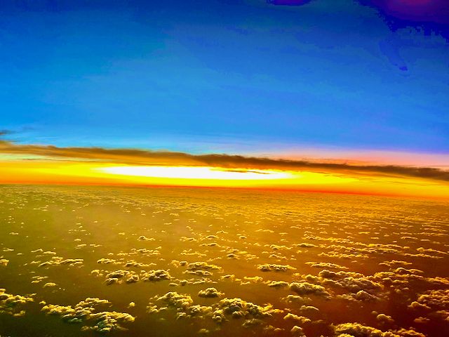 Sun rising with clouds in the foreground, brilliant orange morning glow.