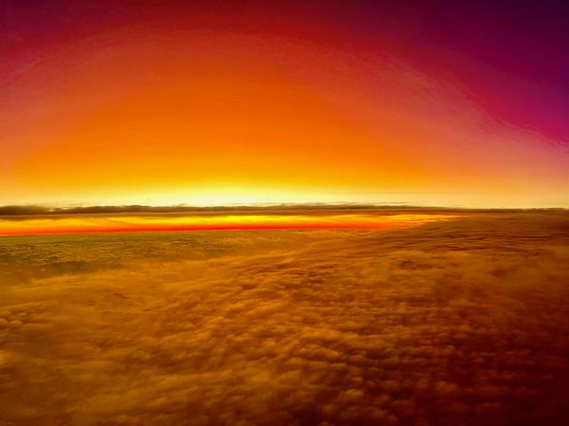 Sun rising with clouds in the foreground, brilliant orange morning glow.